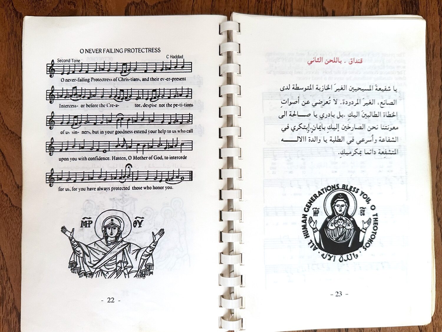 كتيّب القداس مفتوحًا على ترنيمة «يا شفيعة المسيحيين الغير الخازية» بالإنكليزية مع النوتة الموسيقية، وبجانبها الترنيمة نفسها بالعربية