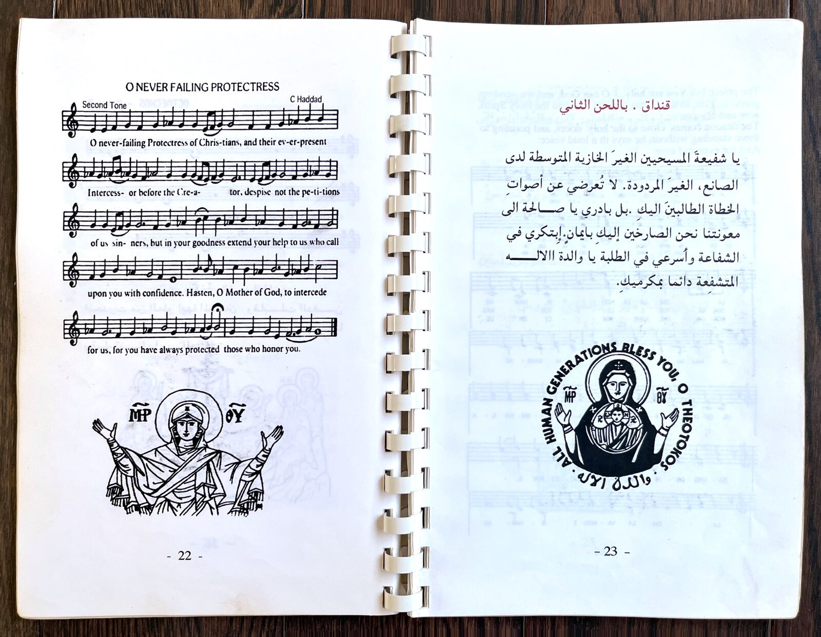 كتيّب القداس مفتوحًا على ترنيمة «يا شفيعة المسيحيين الغير الخازية» بالإنكليزية مع النوتة الموسيقية، وبجانبها الترنيمة نفسها بالعربية